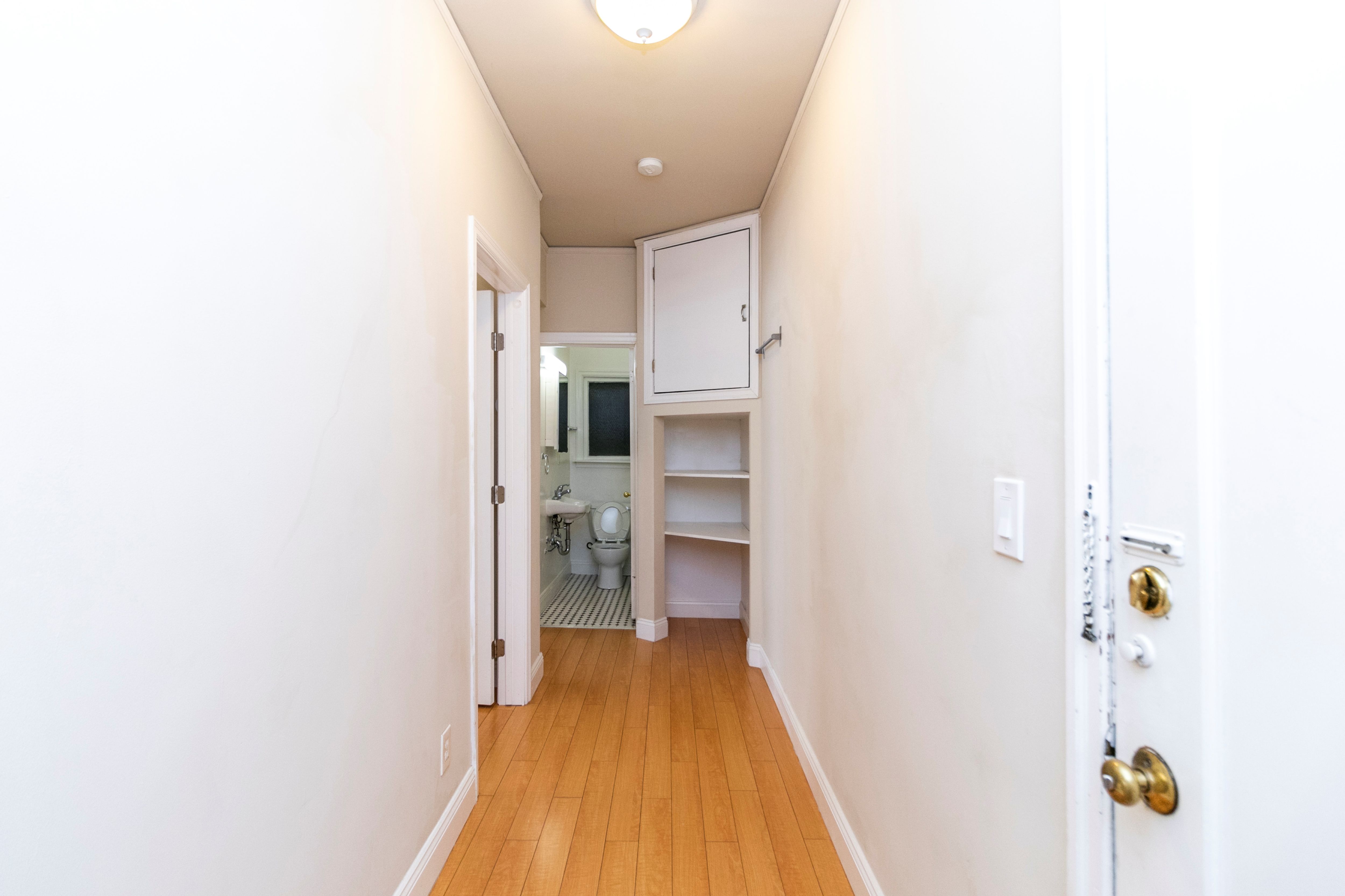 A hallway with a white door and a white wall.